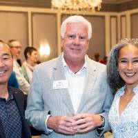 Three event attendees standing together, looking at camera and smiling